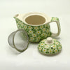 A small herbal teapot in light green ceramic with white and yellow daisies for brewing herbal tea and herbal tea cups
