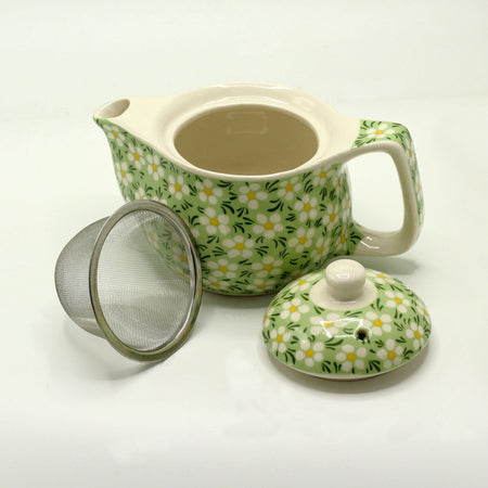 A small herbal teapot in light green ceramic with white and yellow daisies for brewing herbal tea and herbal tea cups