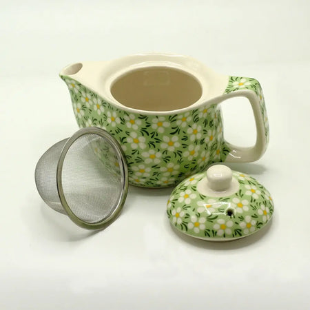 A small herbal teapot in light green ceramic with white and yellow daisies for brewing herbal tea and herbal tea cups