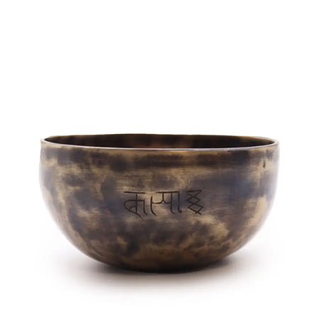 Small indian moon phase singing bowl made of hand-forged bronze with a mottled patina and engraved tibetan script
