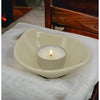 Cream-colored ceramic heart-shaped candle holder with a lit white tea light on a small leaf-shaped ceramic plate