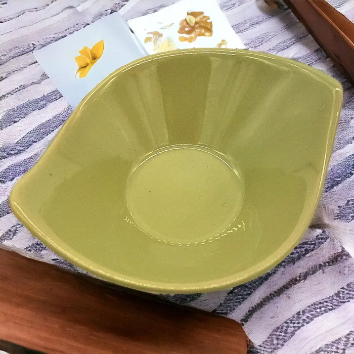 A small olive green leaf shaped ceramic plate with a glossy finish in olive green brown and ivory tones