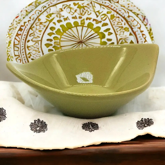 A small olive green ceramic leaf shaped plate with an angular design and smooth glossy finish