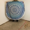 A small cotton beach towel with a blue and white mandala pattern and fringed edges measuring 130cm round