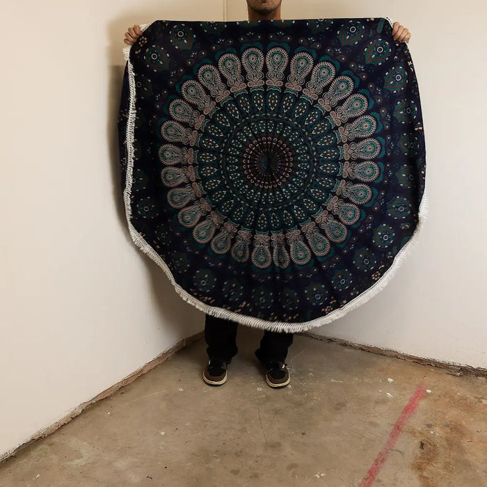 Dark blue circular cotton beach towel with teal and white mandala pattern and fringed edges peacock blues design
