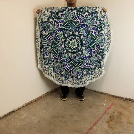 A small mandala roundie cotton beach towel in teal and blue with white accents and a fringed edge measuring 130cm