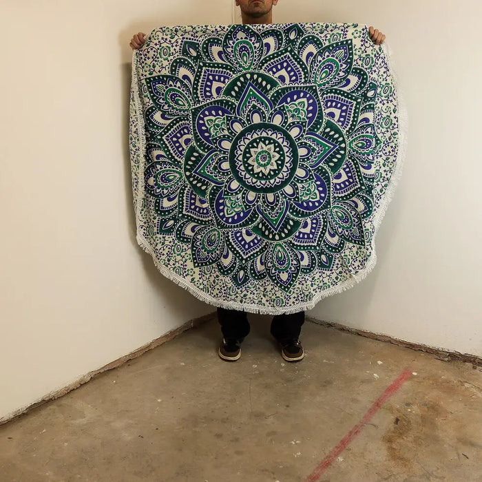 A small mandala roundie cotton beach towel in teal and blue with white accents and a fringed edge measuring 130cm