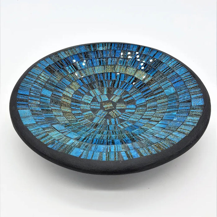 Small mosaic tile dish in blue with gold glitter featuring a circular bowl with blue and black glass tile rings and dark rim