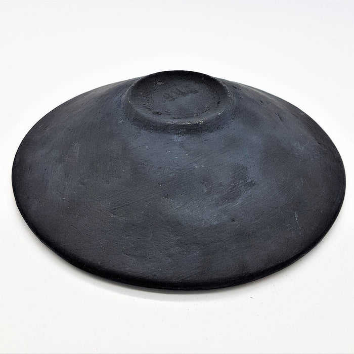 A small mosaic tile dish in green with a matte black handcrafted clay bowl featuring a textured surface and center indentation
