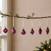 A set of five vibrant classic pink mouth-blown glass baubles shaped as heart star round teardrop and acorn on a branch