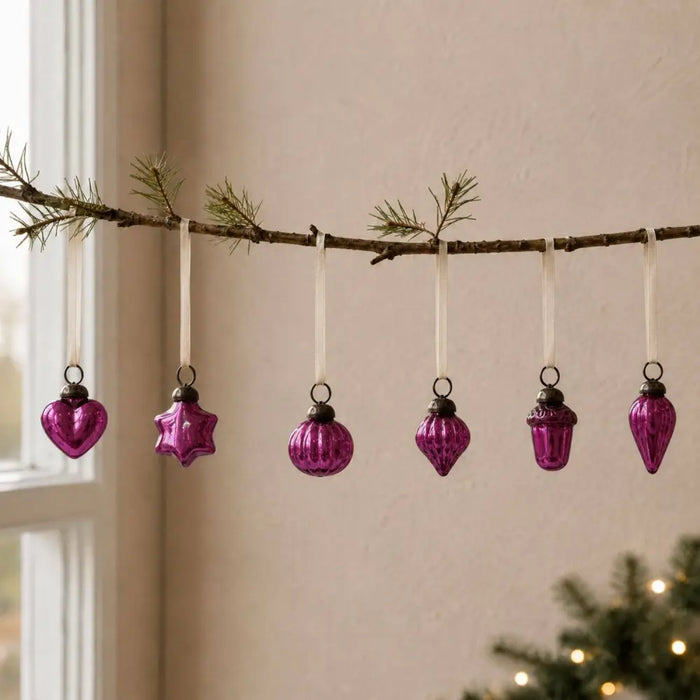 A set of five vibrant classic pink mouth-blown glass baubles shaped as heart star round teardrop and acorn on a branch