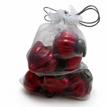 Small red glossy mouth-blown glass baubles with dark caps inside a sheer white organza bag
