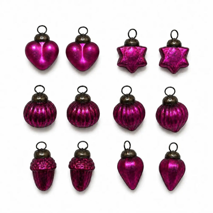 Small mouth-blown glass baubles in vibrant fuschia shaped like hearts stars pumpkins acorns and teardrops with silver caps