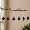 A set of five deep purple mouth-blown glass baubles with gold caps hanging from white ribbons for christmas decor
