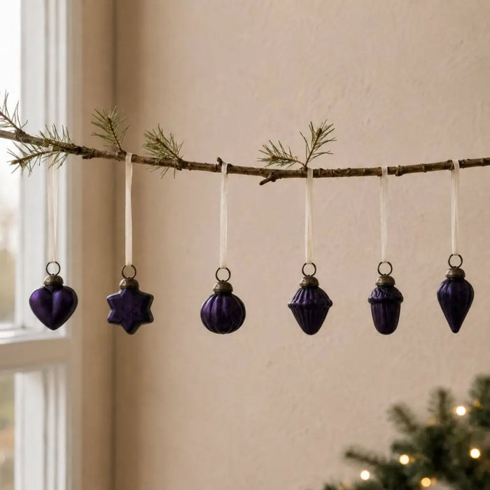 A set of five deep purple mouth-blown glass baubles with gold caps hanging from white ribbons for christmas decor