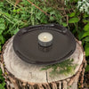 Small oval black ceramic plate holding a lit white tea light candle shown in a home setting