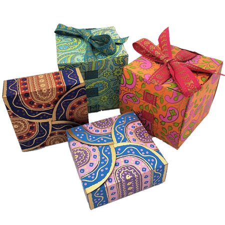 Small printed card gift box set showing four brightly colored paper boxes with decorative ribbons and detailed patterns