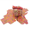 Small printed card gift box with vibrant orange and pink paisley print and a red ribbon bow on top