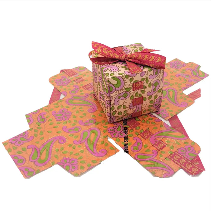 Small printed card gift box with vibrant orange and pink paisley print and a red ribbon bow on top