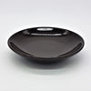 A sleek glossy black ceramic saucer with a smooth rounded rim shown with a small round brown or ivory ceramic plate