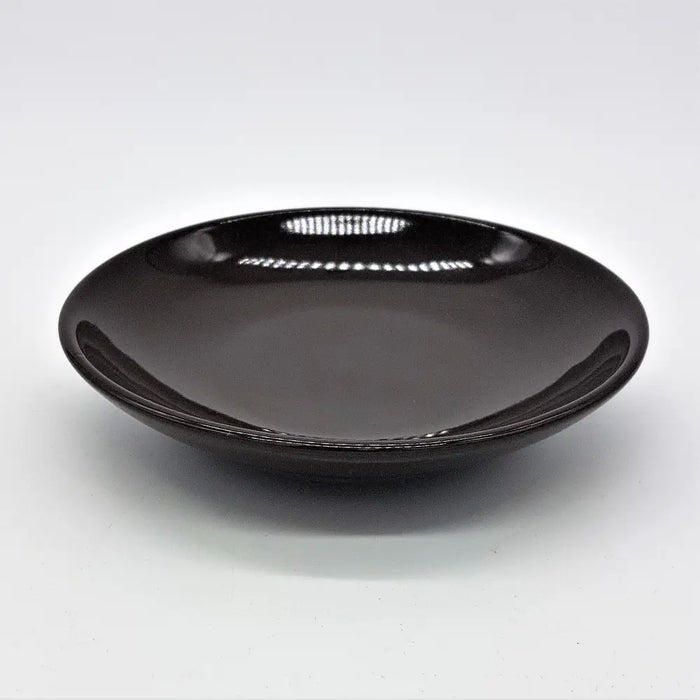 A sleek glossy black ceramic saucer with a smooth rounded rim shown with a small round brown or ivory ceramic plate