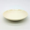 Small round ceramic plate in cream color with a smooth glossy finish and slightly raised rim for serving