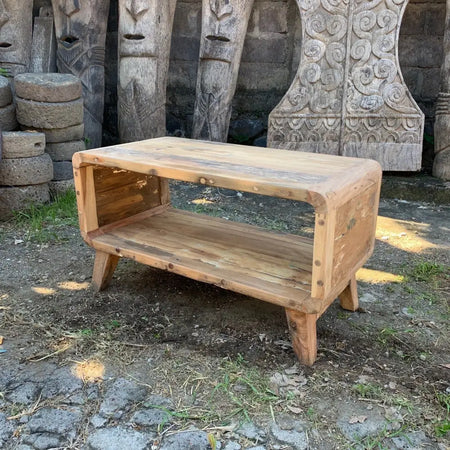 Small round edged coffee table made of rustic light brown recycled wood with a lower shelf and angled legs