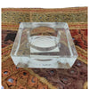 Small square clear glass tealight holder with a central circular well for holding a candle