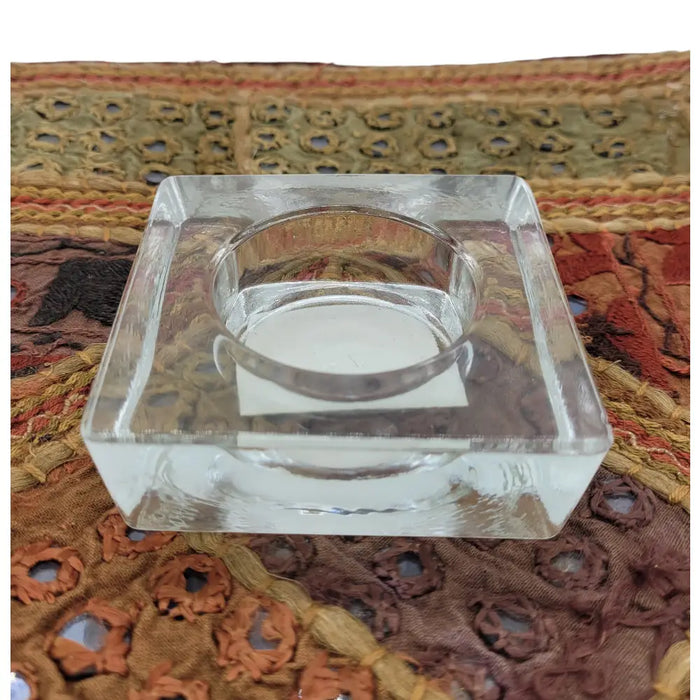 Small square clear glass tealight holder with a central circular well for holding a candle