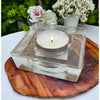 Small square glass tealight holder in clear with a silver rim holding a white candle inside