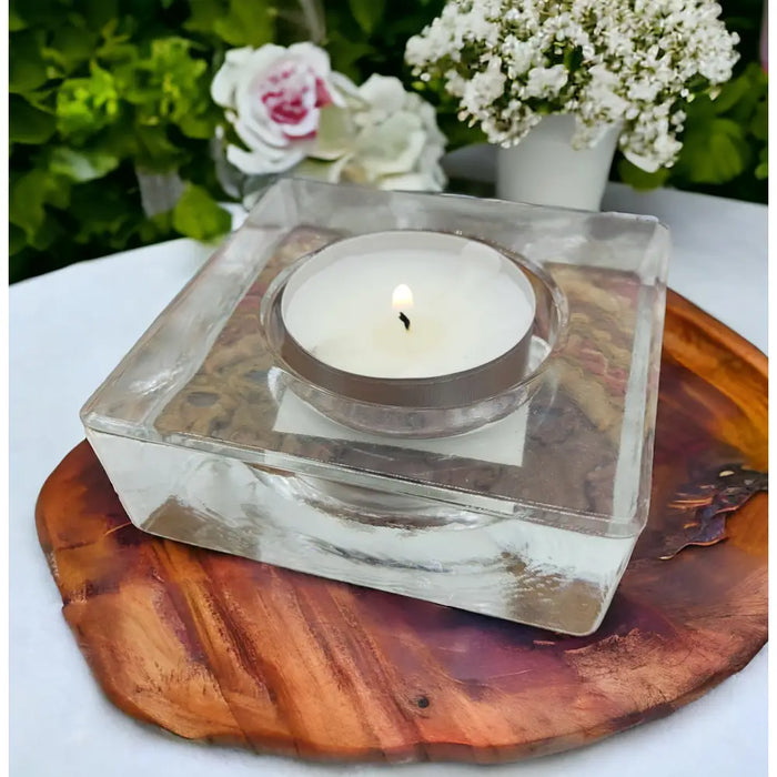 Small square glass tealight holder in clear with a silver rim holding a white candle inside