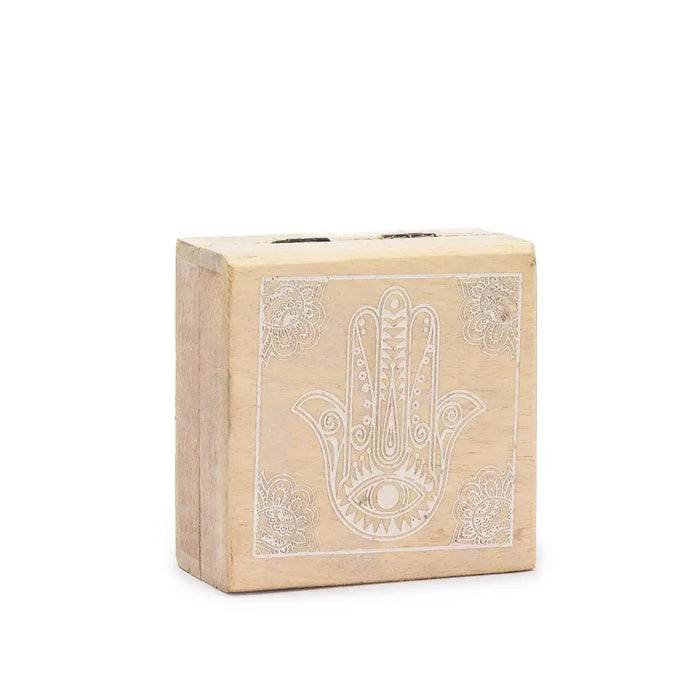 A small square wooden box in whitewash featuring an intricately engraved hamsa hand with a central eye motif