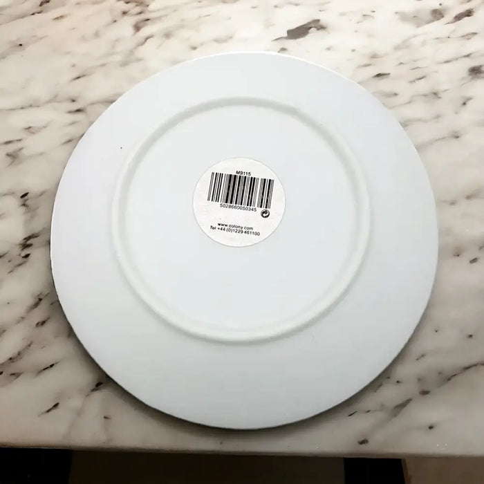Small white porcelain plate with swirl pattern and a barcode sticker in the center on a white background