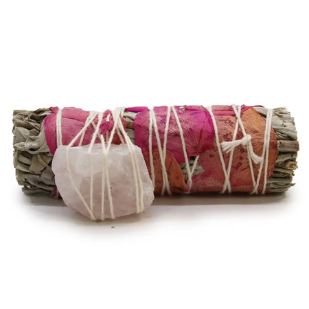 A rolled bundle of love spirit sage tied with white string and decorated with pink and orange rose petals plus quartz crystal