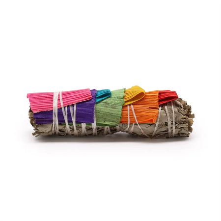 A colorful smudge stick of white sage and 7 corn leaves wrapped with vibrant pink purple green yellow and orange ribbons