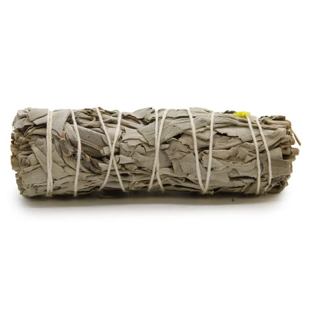 A smudge stick of white sage and blue sage leaves tied with natural twine and a small yellow tag on one end
