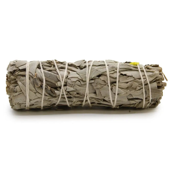 A smudge stick of white sage and blue sage leaves tied with natural twine and a small yellow tag on one end
