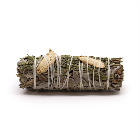 A smudge stick of white sage bound with light twine featuring dried ginger and cedar pieces in natural colors