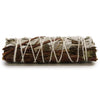 A smudge stick of white sage and peppermint with silvery gray leaves and brown stems tied with white twine