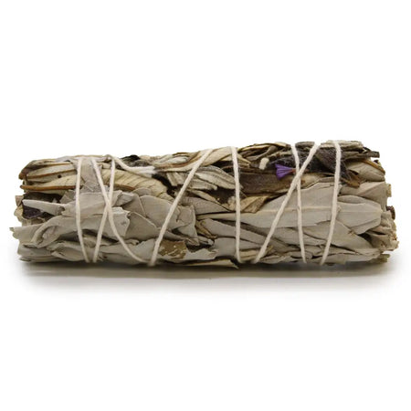 A smudge stick of dried white sage and yerba santa tied with natural twine showing gray, beige, and purple leaves