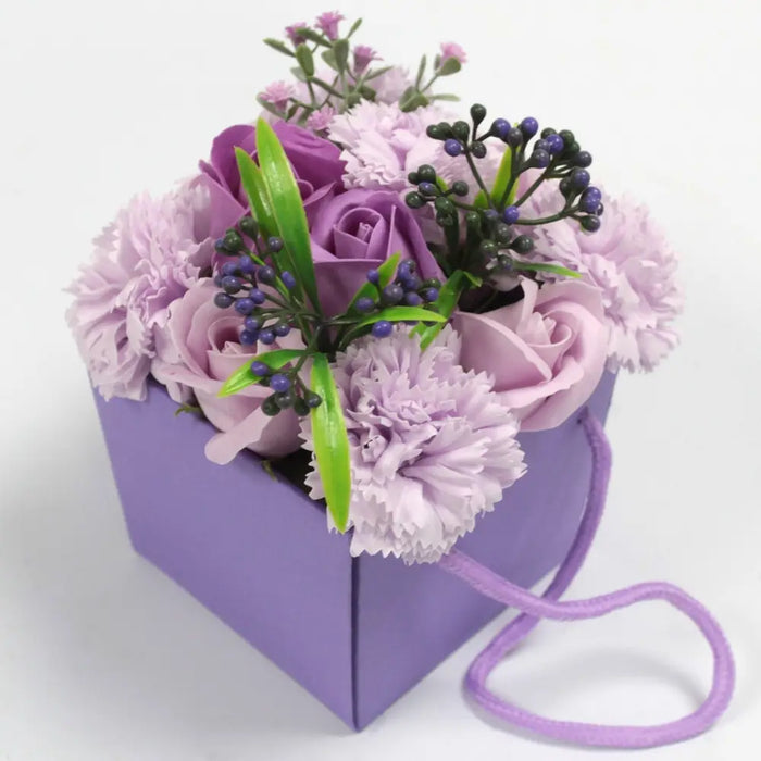 Purple soap flowers arranged with lavender rose and carnation in a matching lavender box with fabric handle