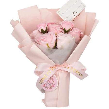A soap flower bouquet of soft pink roses wrapped in blush paper tied with a love is eternal ribbon and gift card