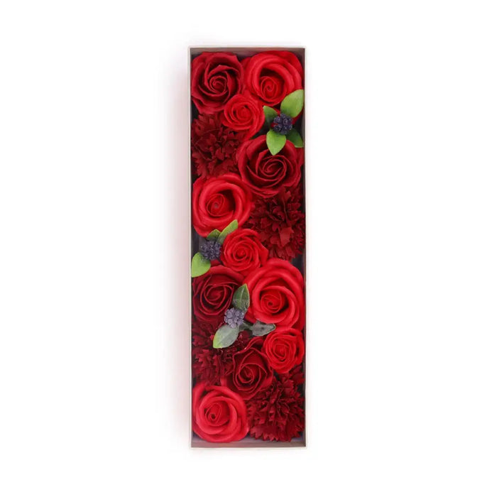 A soap flower gift box with vibrant red roses and dark red soap carnations accented by green leaves and purple flowers