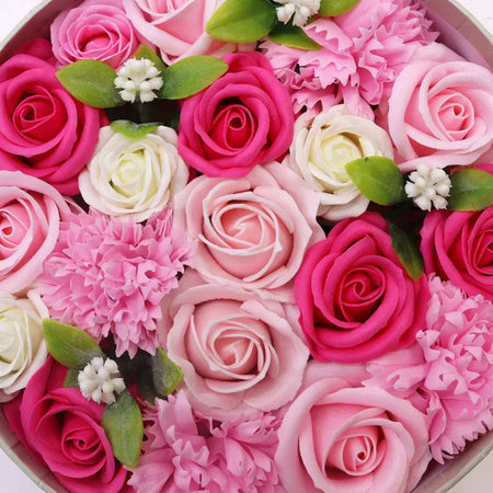A round flower gift box with pink magenta and white soap flowers accented by green leaves and tiny white flowers