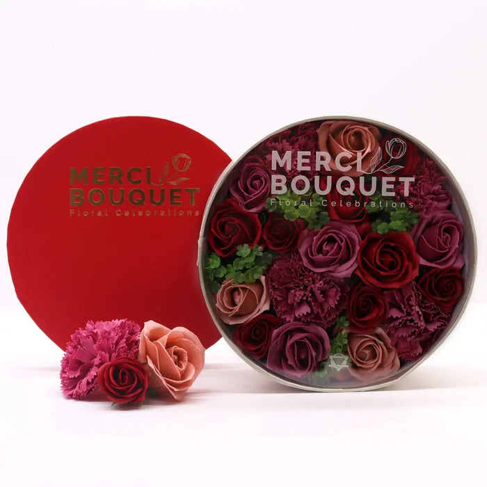 A round red-lidded flower gift box with dense artificial soap flower gift vintage red roses in burgundy pink hues