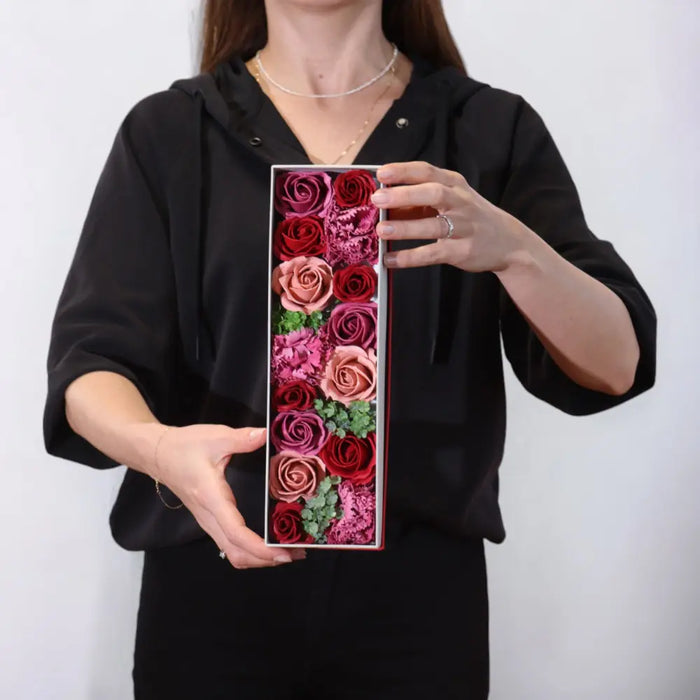 A soap flower gift box with preserved roses in red pink and mauve accented by greenery in a vintage style roses collection