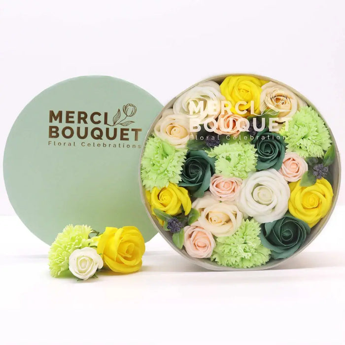 A round light green flower gift box with colorful soap flowers in yellow pink white and green for spring celebrations
