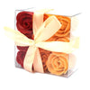 A clear plastic box holds six bath soap roses in deep red and warm orange tied with a cream satin ribbon