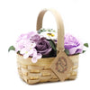 A medium wicker basket with a natural wood handle filled with lilac and white soap flowers
