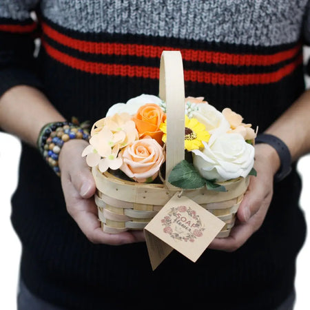 A woven wicker basket filled with soap flowers in peach orange white and yellow colors medium size